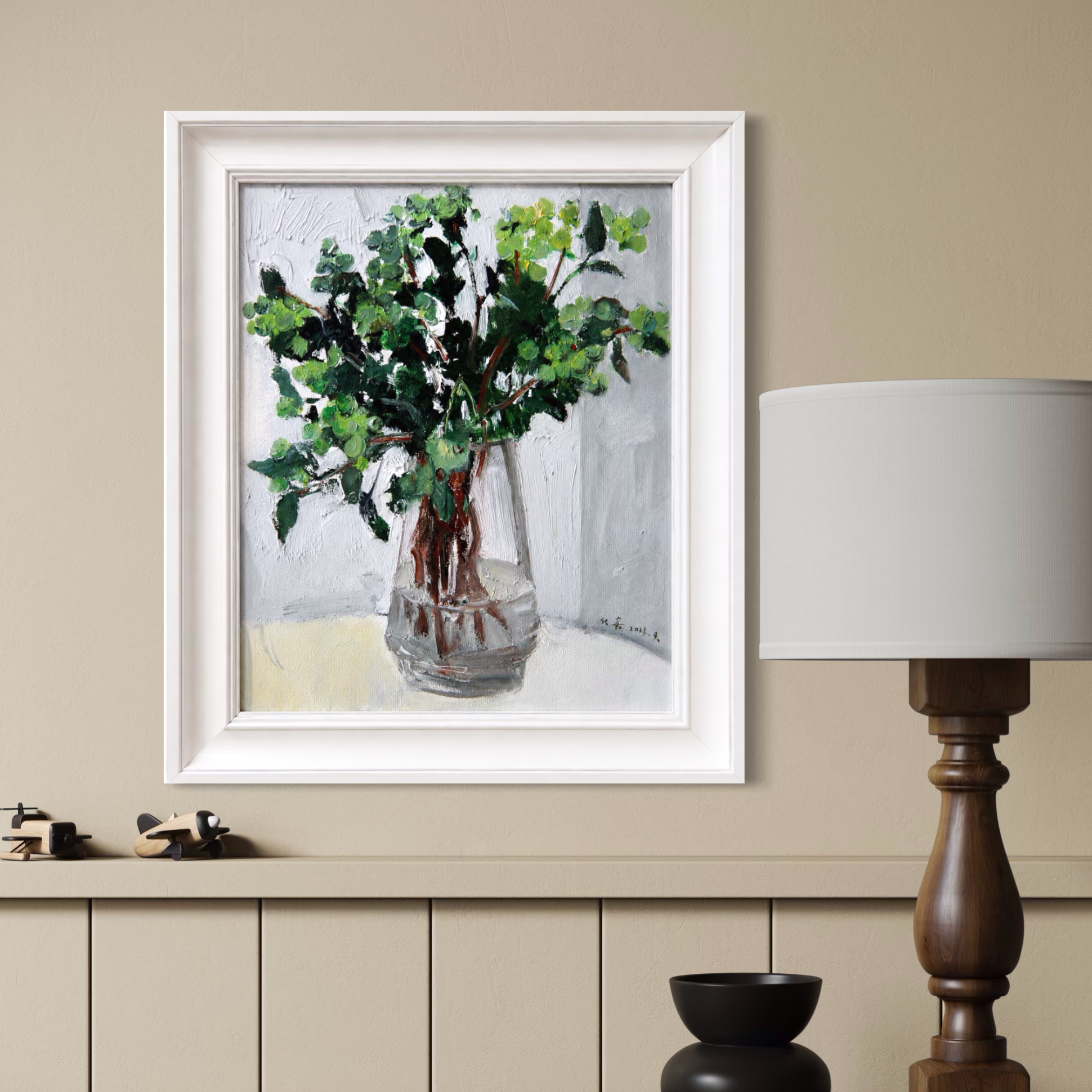 Framed greenery oil painting displayed in a warm contemporary interior with soft lighting and refined neutral furnishings.