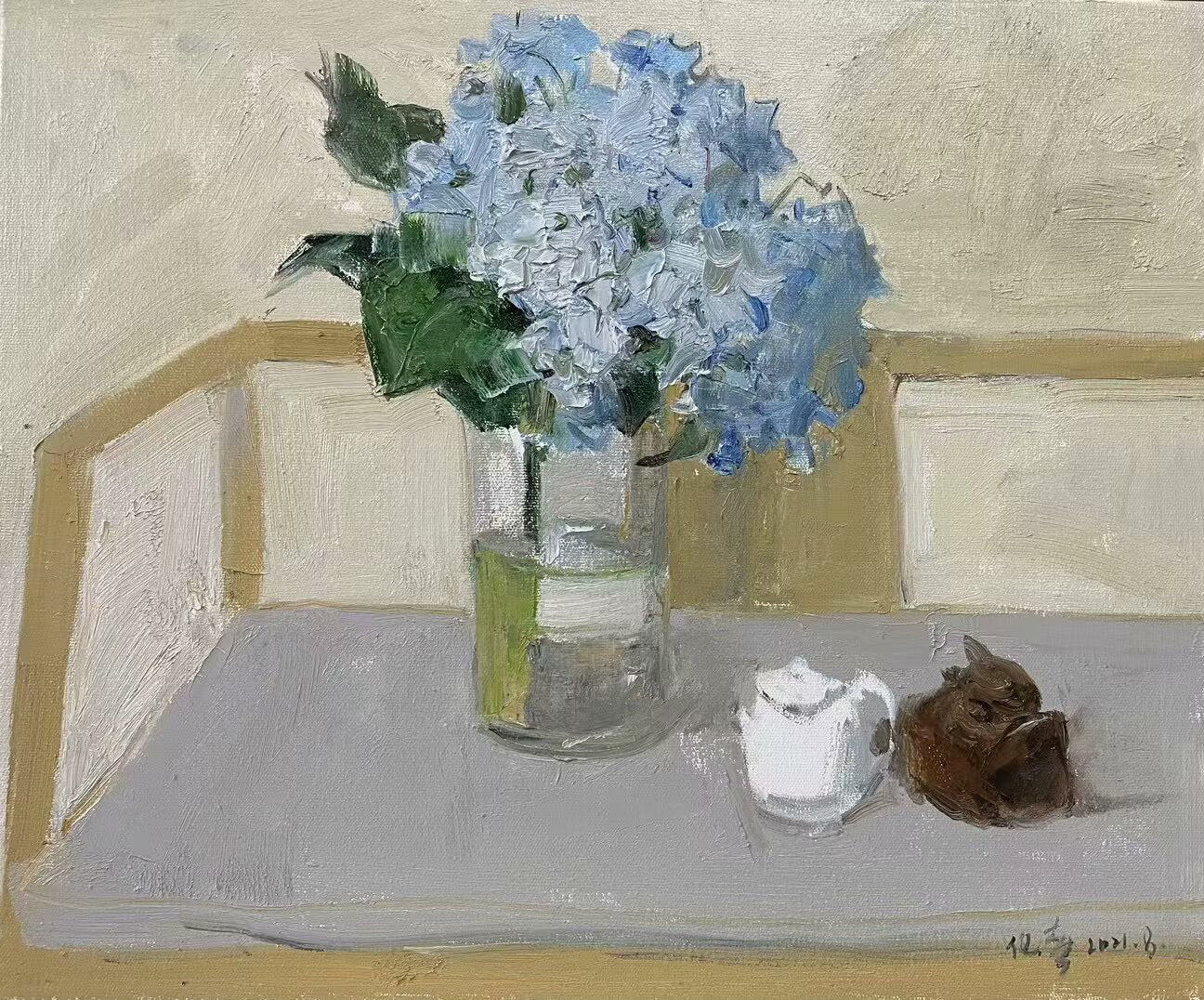 Detail of blue hydrangea flowers, glass vase, and decorative objects arranged within a minimalist interior setting.