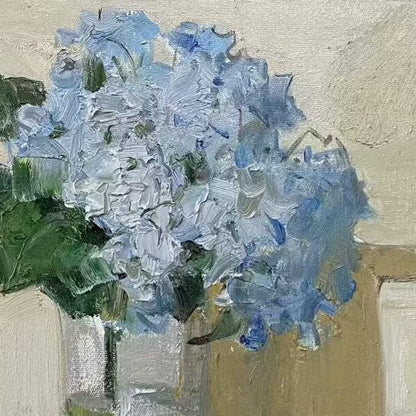 Detailed view of blue hydrangea flowers arranged in a glass vase, emphasizing transparency, texture, and the balance of floral forms.