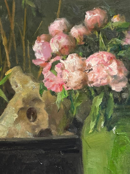 Detail of stacked books and a small sculpture, highlighting the quiet narrative and presence within the composition.