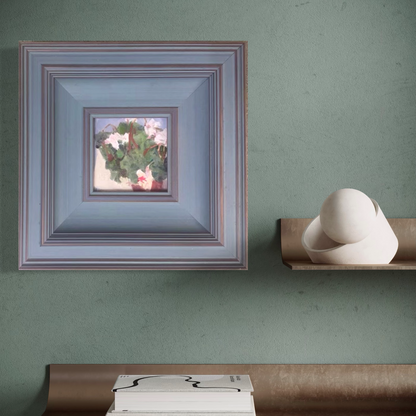Original floral oil painting framed in muted blue wood, displayed against a soft green wall in an elegant and modern interior setting.