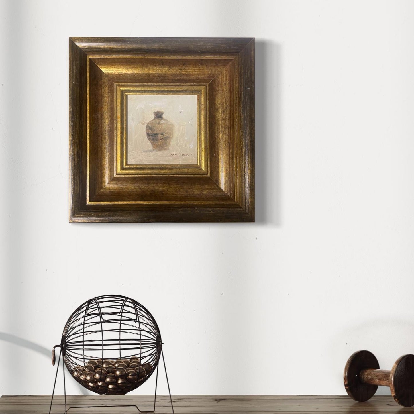 Small classical still life oil painting framed in antique gold wood, styled in a refined modern living space with minimalist black and white decor.