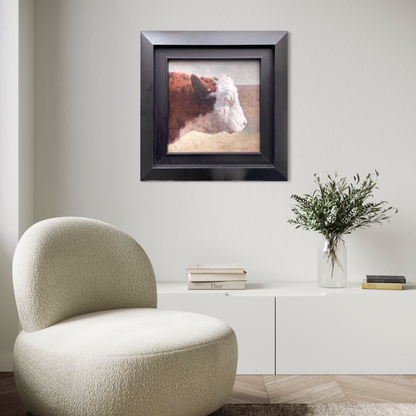 A framed original cow portrait oil painting displayed in a minimalist living room with soft neutral tones and modern furniture, adding warmth, texture, and quiet character to the interior space.