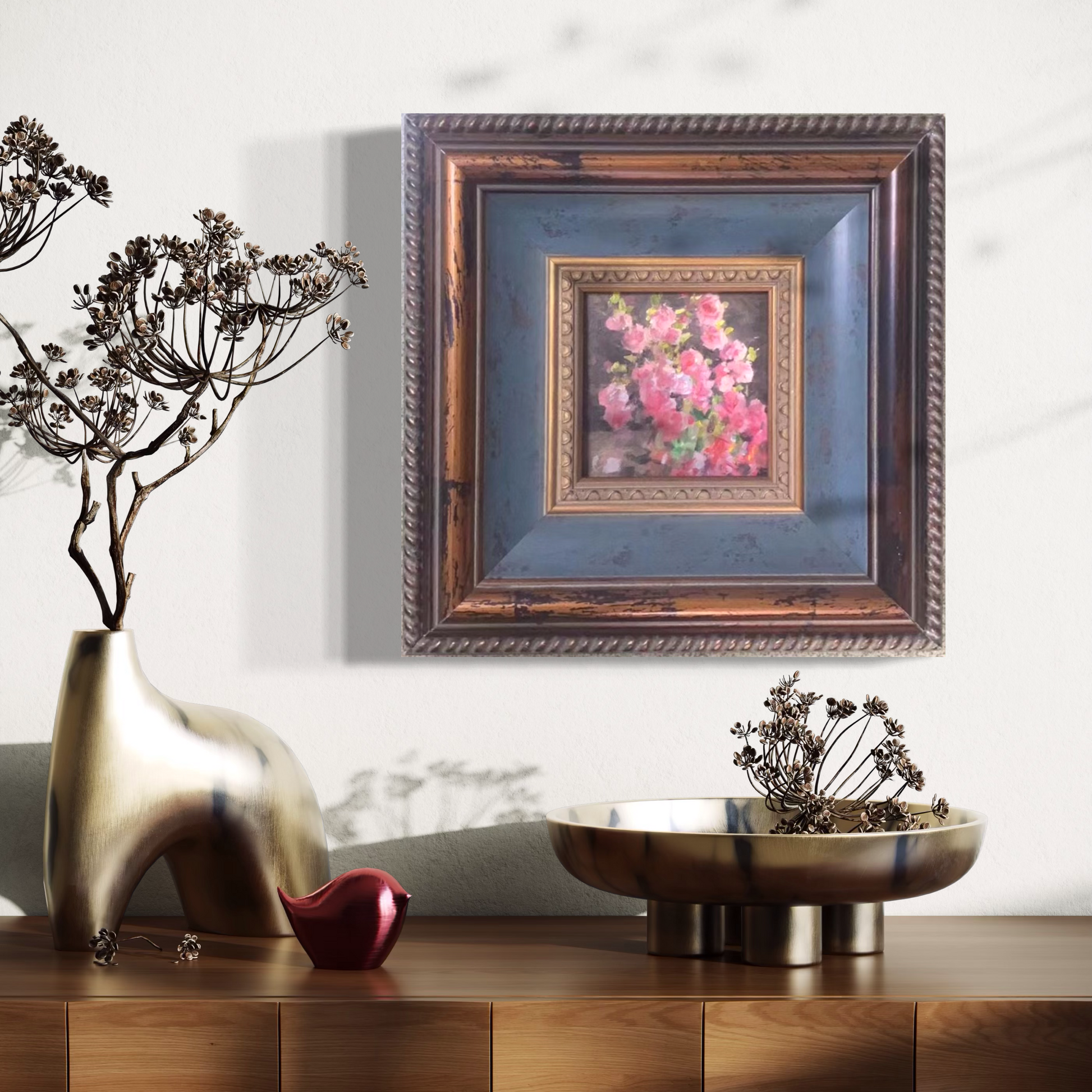 Small framed pink floral oil painting styled in a warm contemporary interior with sculptural decor and soft ambient lighting.