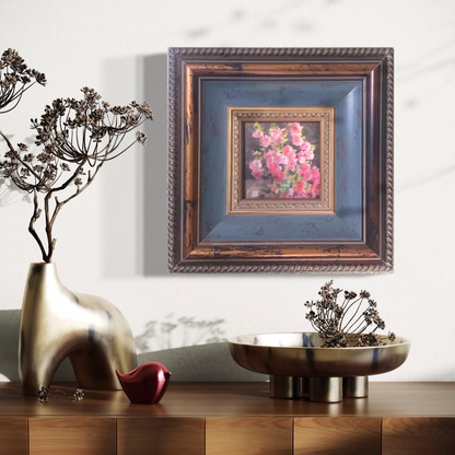 Small framed pink floral oil painting styled in a warm contemporary interior with sculptural decor and soft ambient lighting.