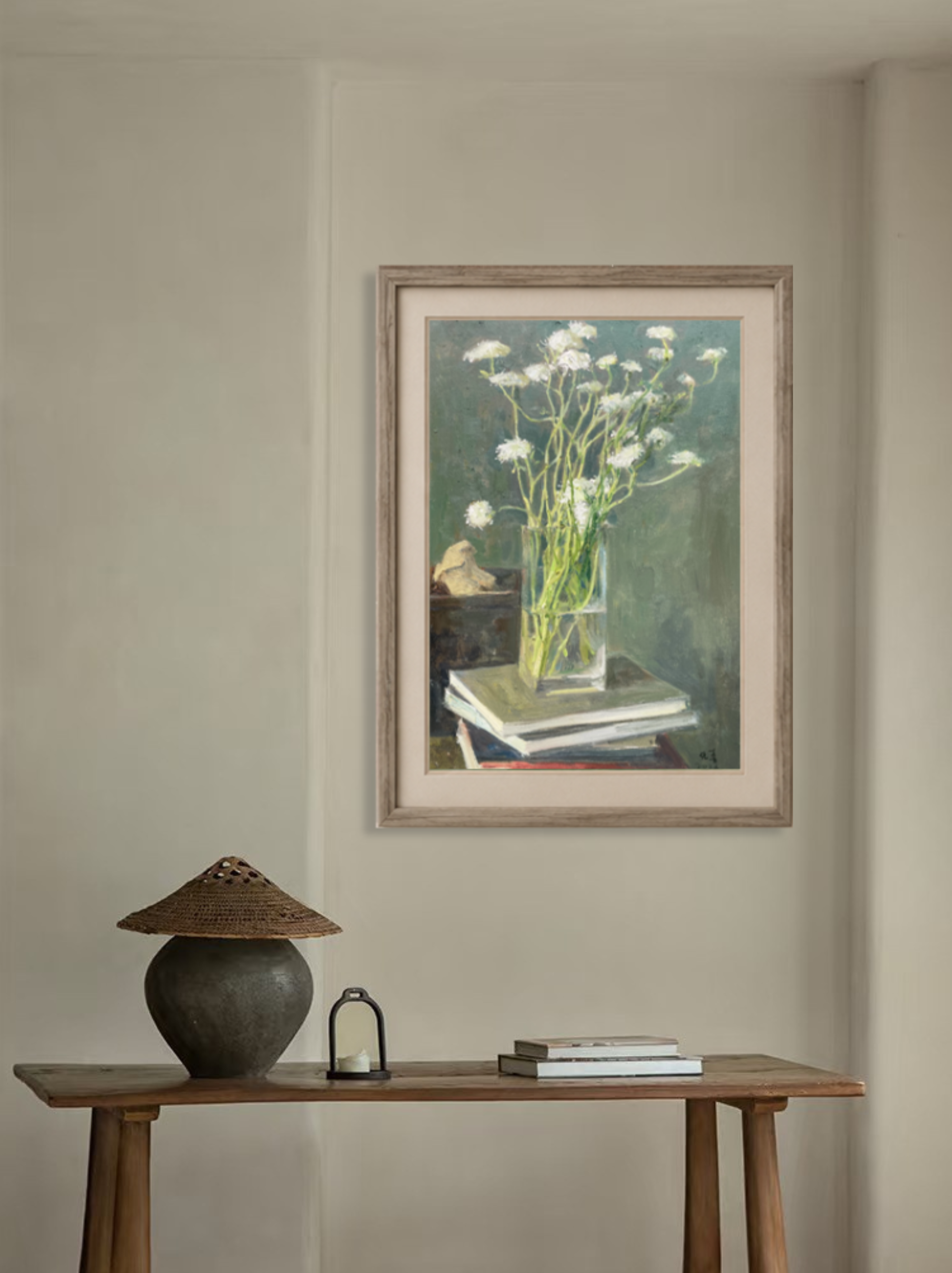 Original oil painting featuring white flowers in a glass vase displayed above a wooden cabinet, adding serenity and elegance to the interior space.