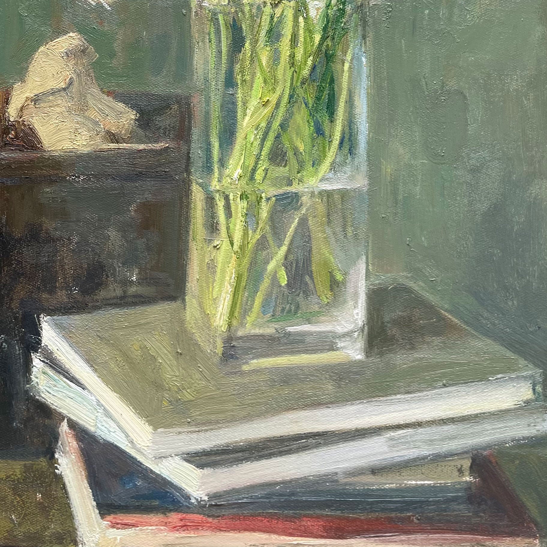 Close-up of the glass vase atop stacked books, emphasizing transparency, reflections, and balance of the still life composition.