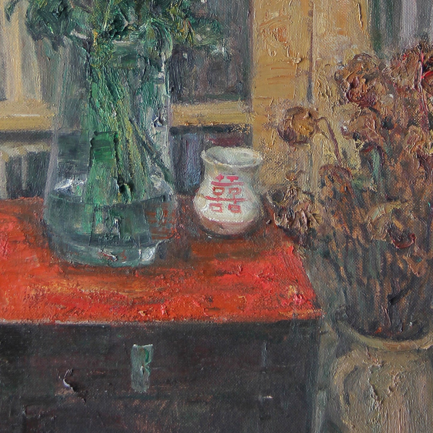 Close-up of a green glass vase placed on a red tabletop, showing reflections, color contrast, and painterly surface texture.