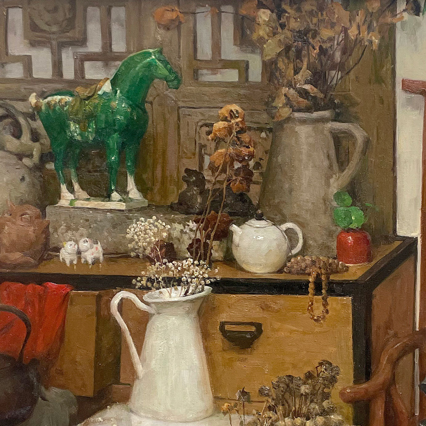 Close-up detail of a green horse sculpture surrounded by books, ceramics, and collected objects, highlighting texture, color contrast, and visual depth.