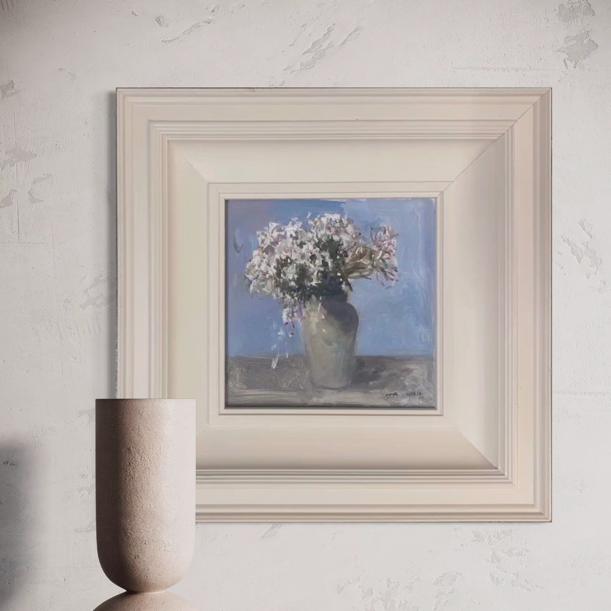Small floral oil painting framed in cream-toned wood, displayed against a refined neutral wall with modern interior styling.