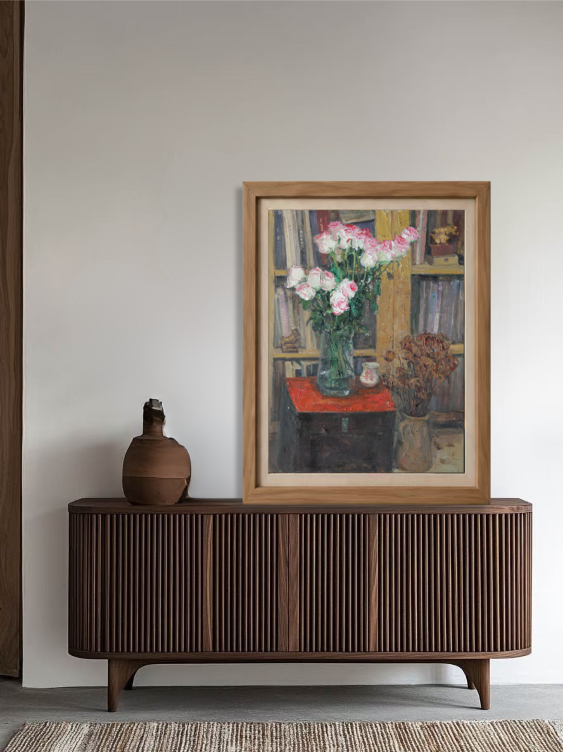 Framed oil painting featuring pink roses, books, and interior objects displayed above a wooden sideboard, creating a sophisticated focal point within the room.