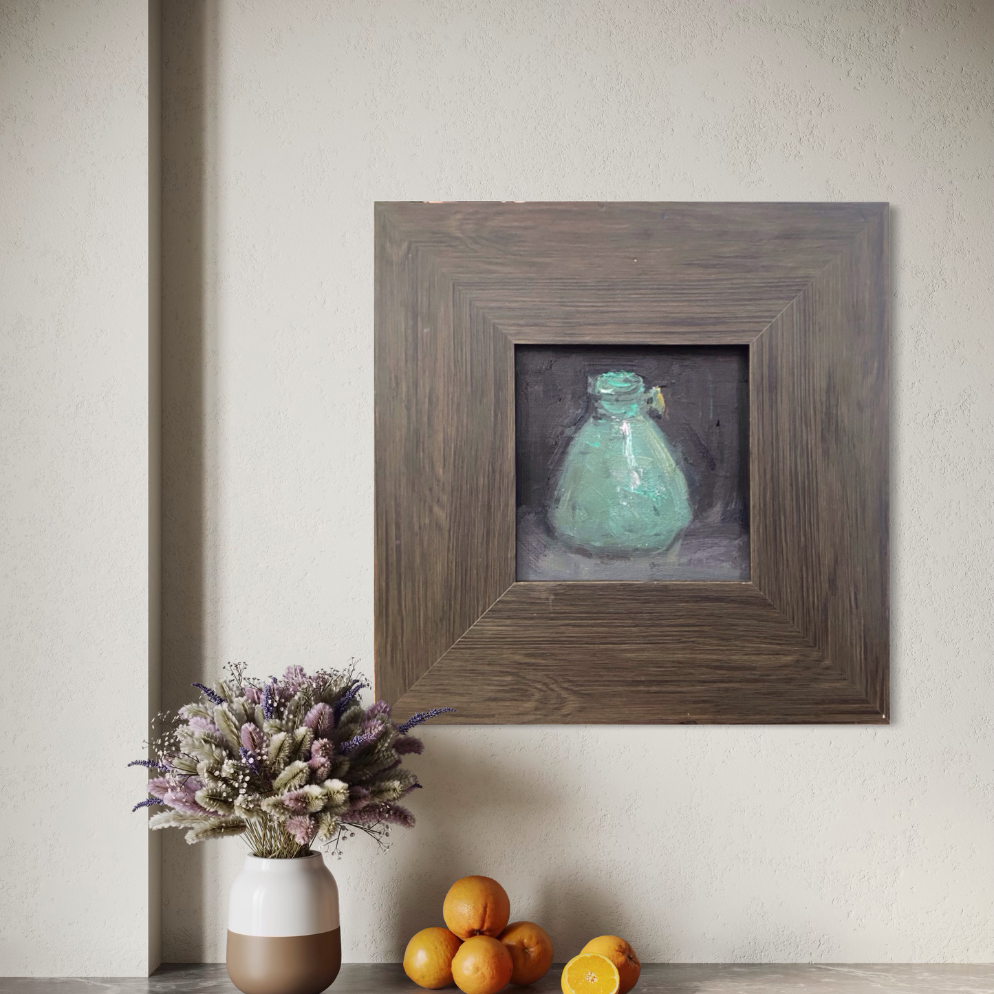 Original still life oil painting shown above a wooden shelf with ceramic objects. The earthy frame and restrained composition create a warm and collected interior atmosphere.