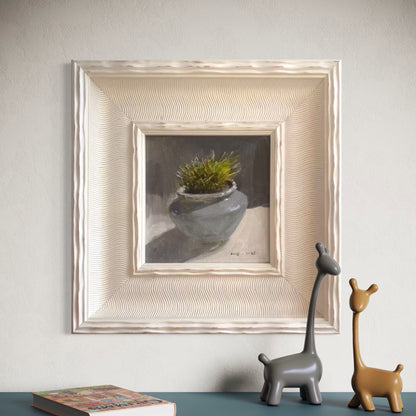 A small framed botanical oil painting displayed in a minimalist contemporary room with soft beige walls and sculptural decor, creating a refined gallery-style atmosphere
