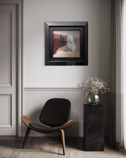A small framed cow portrait painting displayed in a calm neutral home interior with soft lighting and minimal furnishings, bringing a quiet rural atmosphere into the modern space.