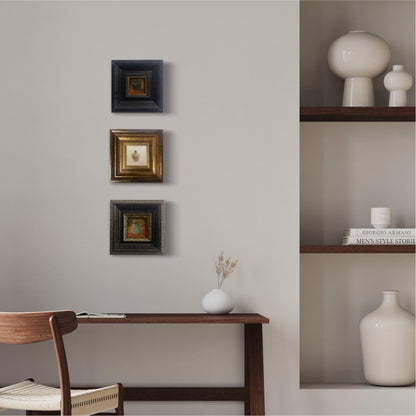 Collection of small framed still life oil paintings arranged as a gallery wall in a modern minimalist interior.