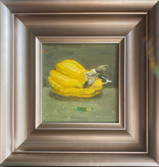 A small original oil painting featuring a yellow squash resting against a muted olive background, presented in a dark walnut-toned wooden frame. The artwork combines soft light, textured brushwork, and quiet still life composition for a refined gallery-style presentation.