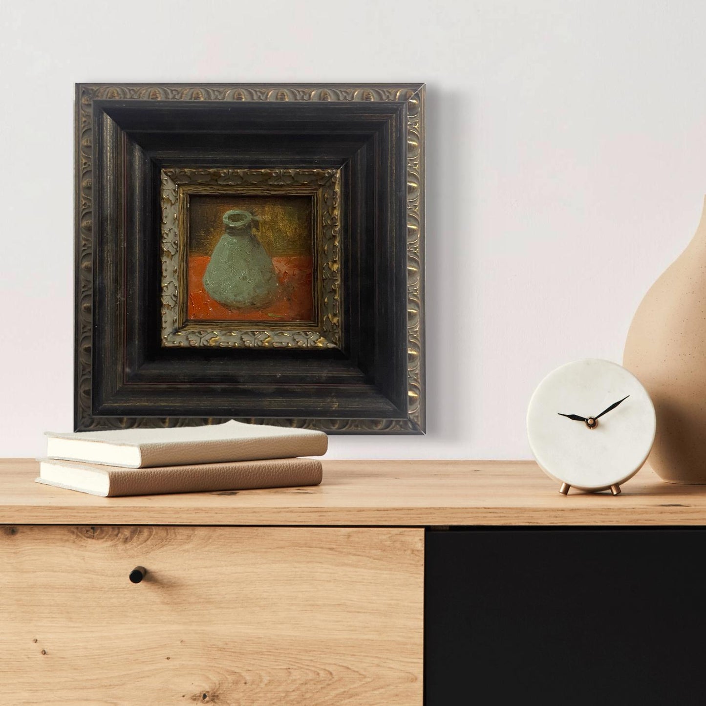 Original still life oil painting in an antique-inspired black and gold frame displayed in a warm contemporary living space.