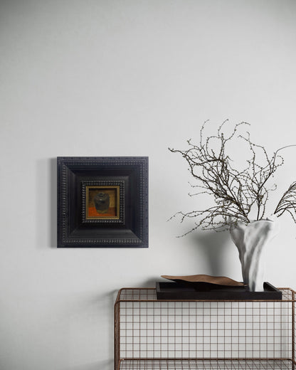 Small classical still life painting in a deep black frame displayed on a neutral wall with soft natural lighting and refined interior styling.