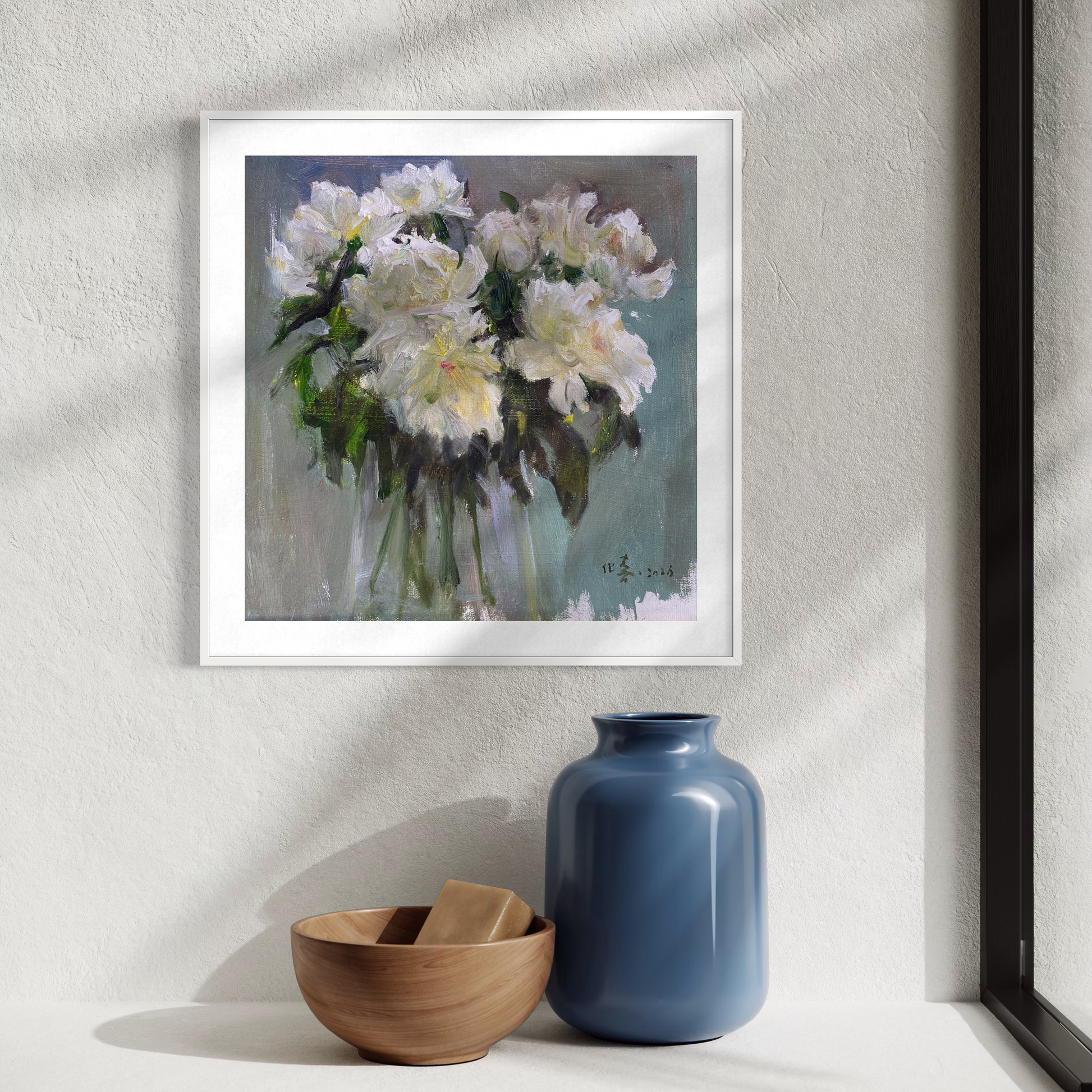 Framed white floral oil painting displayed in a calm modern interior with ceramic decor and soft natural lighting.