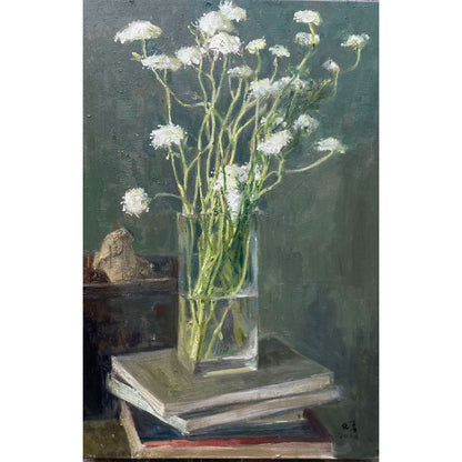 Detail showing white flowers, stacked books, and small decorative objects, revealing layered composition and calm interior atmosphere.