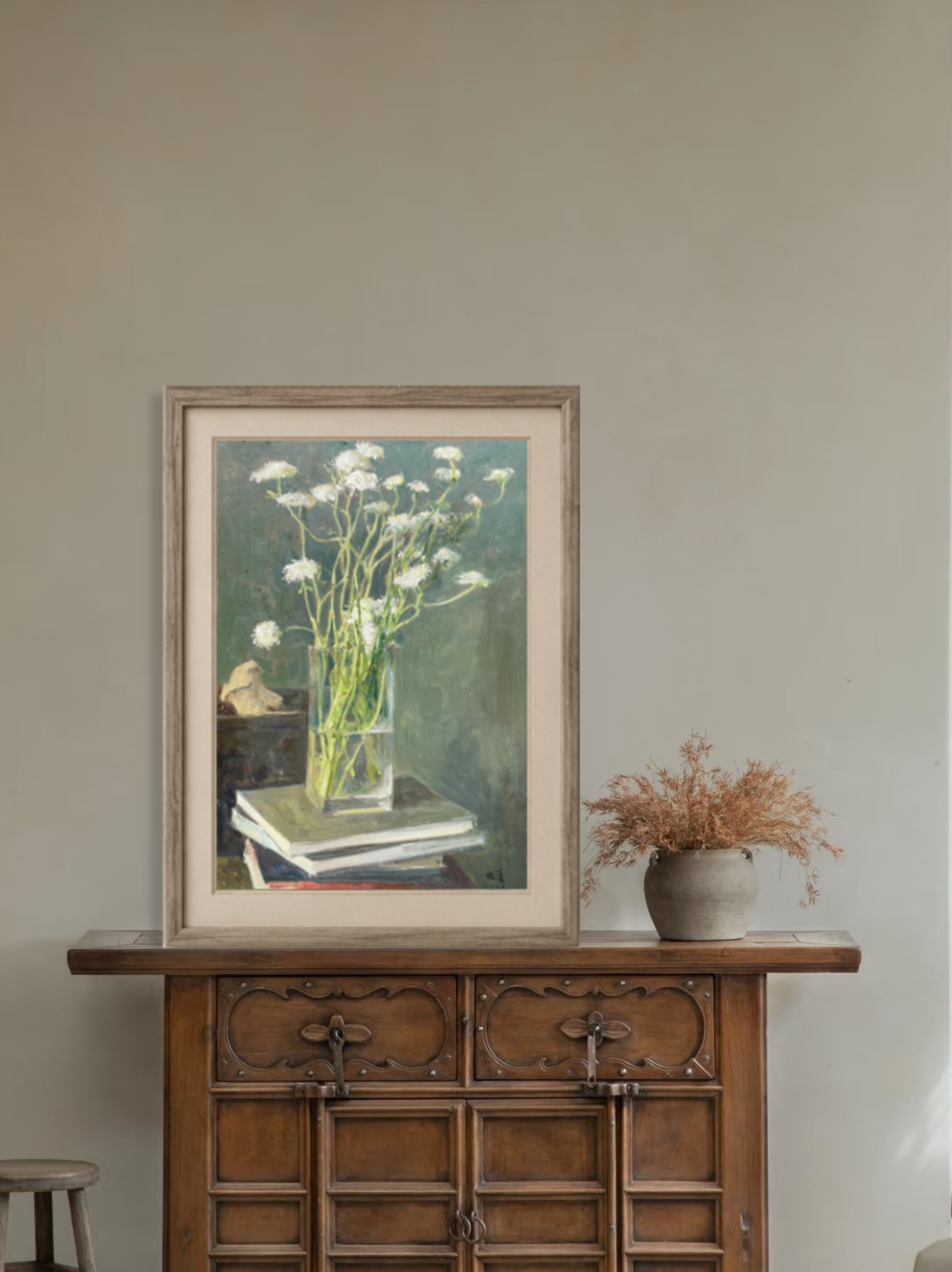 Framed oil painting of white flowers in a glass vase displayed by a window in a calm interior, creating a soft, airy focal point for home decor.