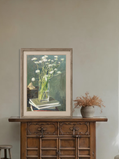 Framed oil painting of white flowers in a glass vase displayed by a window in a calm interior, creating a soft, airy focal point for home decor.