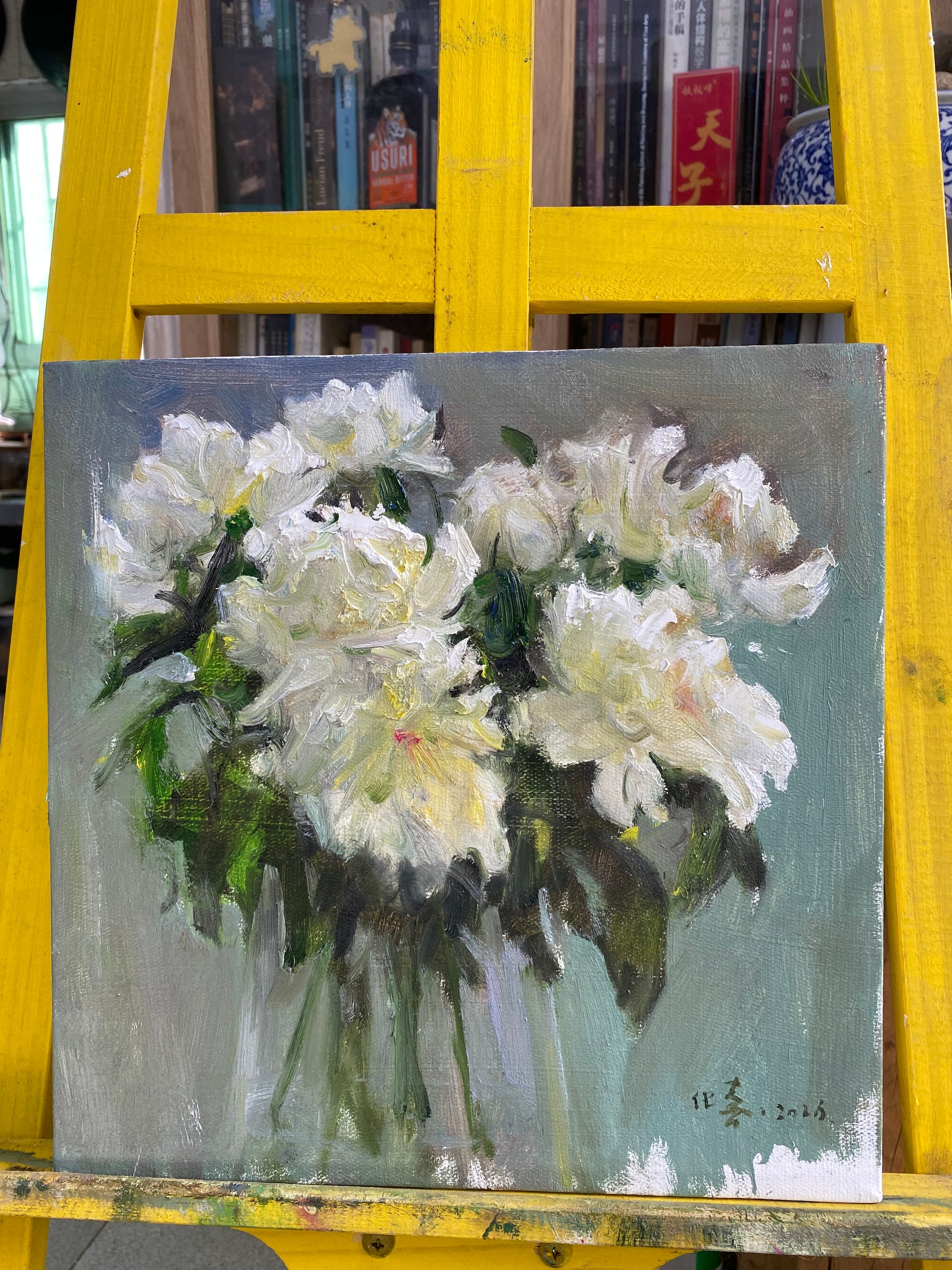 Original white peony oil painting displayed on a studio easel during the framing and presentation process.