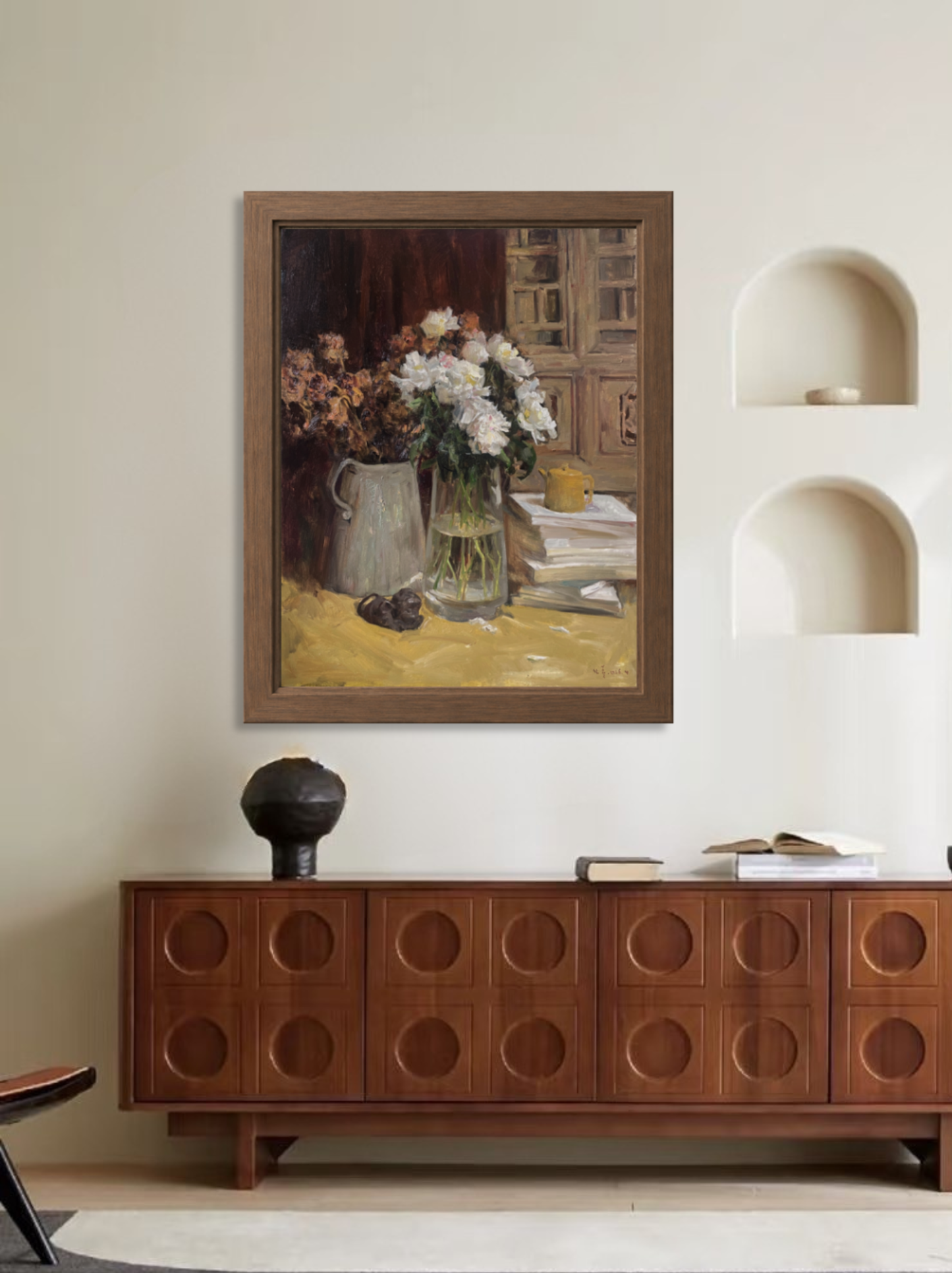 Framed original still life painting displayed in a living room interior above a wooden cabinet.