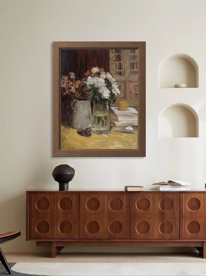 Framed original still life painting displayed in a living room interior above a wooden cabinet.